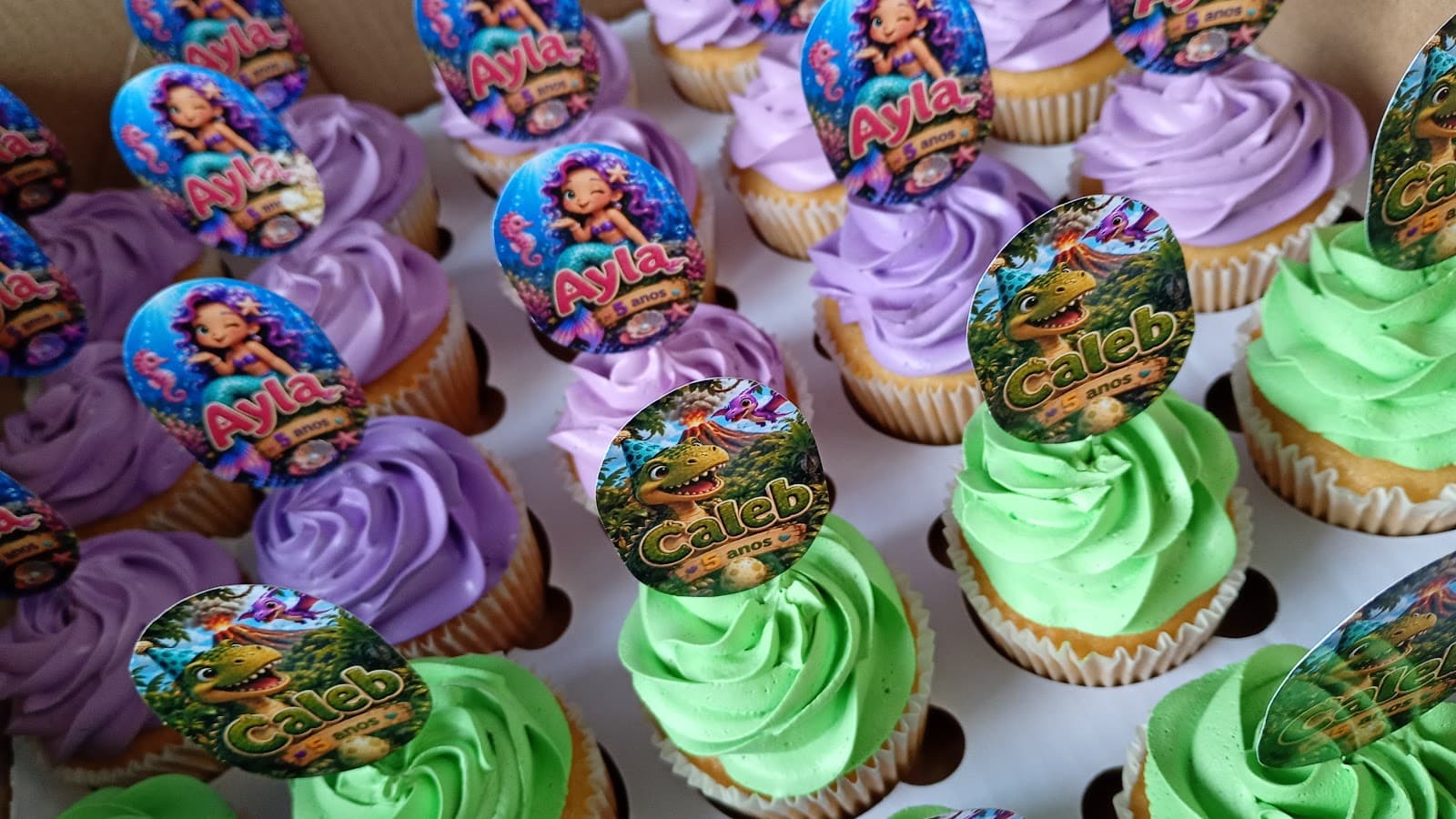 Cupcakes com chantilly lilás e verde e topos personalizados de sereia e dinossauro